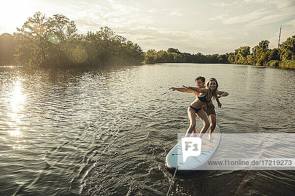Junges Paar genießt den Sommer am See  stehend auf einem Paddelbrett