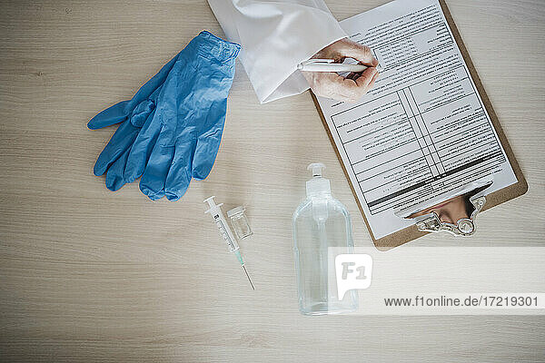 Eine Ärztin schreibt einen Bericht auf einem Klemmbrett neben medizinischen Geräten am Schreibtisch