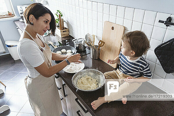 Mutter spricht mit Kind bei der Zubereitung von Essen in der Küche zu Hause