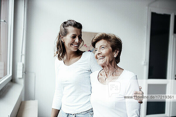 Fröhliche junge Frau  die ihre Großmutter zu Hause betrachtet