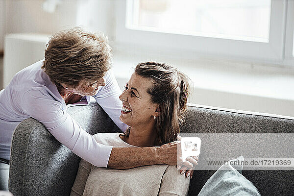 Frau  die ihre Enkelin auf dem Sofa umarmt
