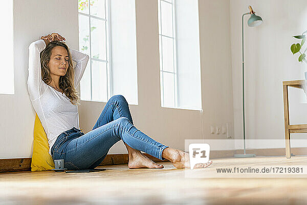 Relaxed woman with eyes closed sitting on floor at home