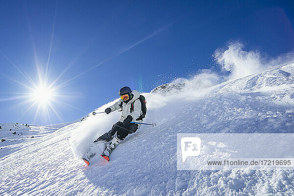 Die Sonne scheint über einem jungen Mann beim Skifahren im Arlberg-Massiv
