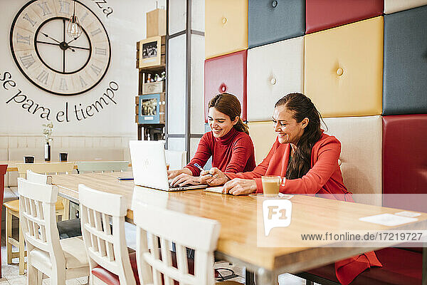 Fröhliche Frauen arbeiten am Tisch in der Cafeteria