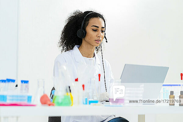 Young female researcher discussing on video call through laptop in laboratory
