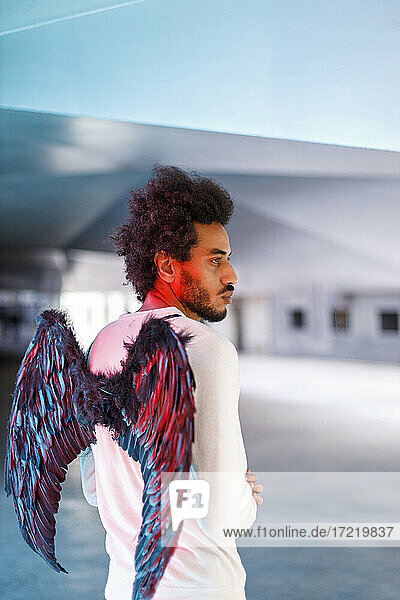 Young man with angel wings looking away