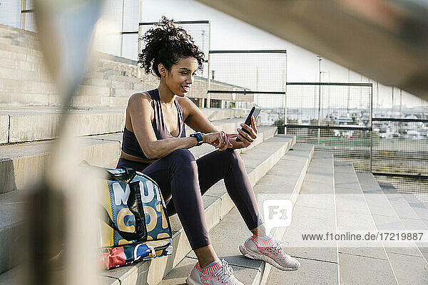 Eine Sportlerin benutzt ein Mobiltelefon  während sie auf einer Treppe sitzt