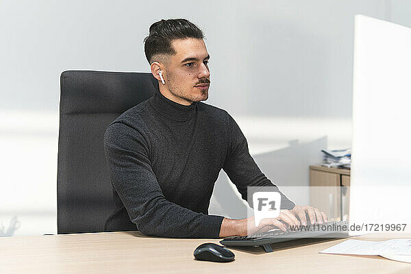 Young businessman working on computer at desk in office