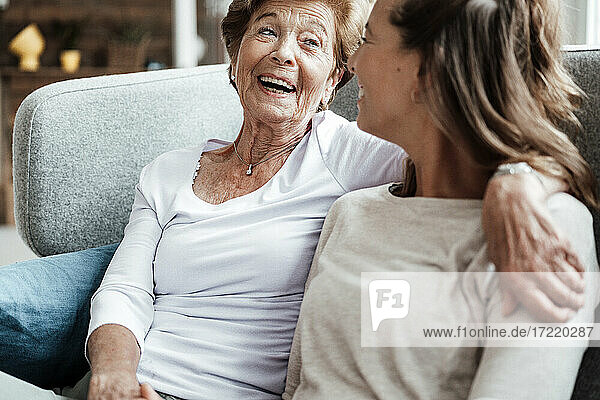 Glückliche Großmutter lacht ihre Enkelin an  während sie auf dem Sofa sitzt