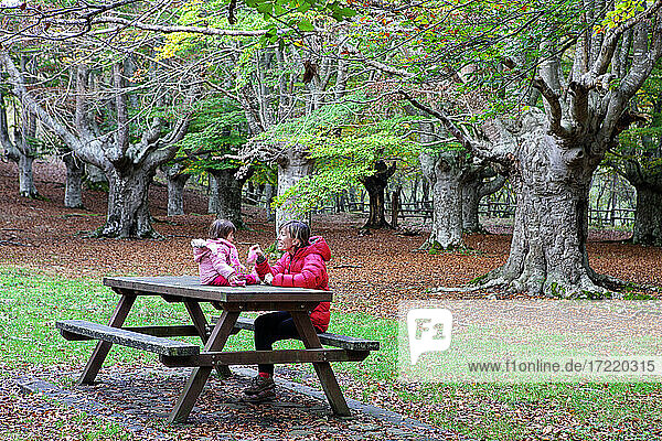 Mutter sitzt mit Tochter auf einer Bank im Naturpark Gorbea