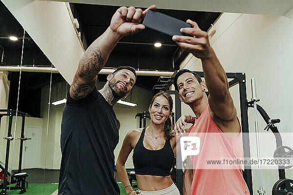 Lächelnde Freunde machen ein Selfie mit ihrem Handy im Fitnessstudio