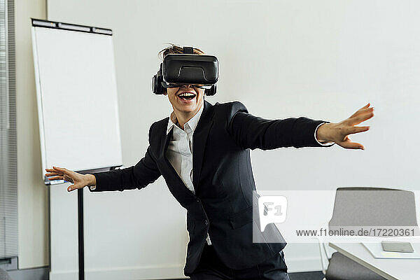 Cheerful female business professional with virtual reality simulator in office