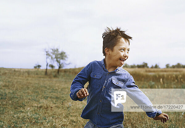 Boy with down syndrome running while looking back over shoulder