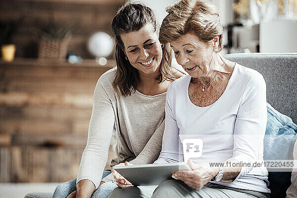 Überrumpelte Seniorin  die von ihrer Enkelin zu Hause ein digitales Tablet benutzt