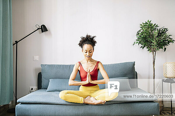 Junge Frau übt Yoga auf dem Sofa zu Hause