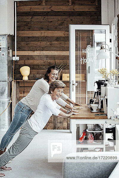 Cheerful young woman with grandmother exercising at countertop