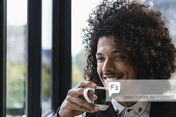 Gutaussehender männlicher Geschäftsmann schaut weg  während er in einem Café Kaffee trinkt