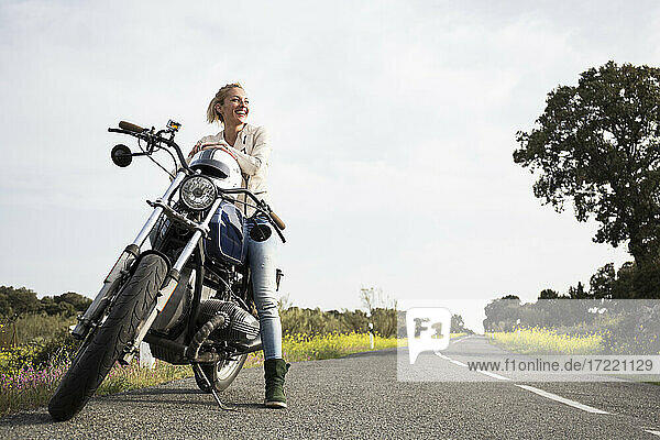 Lächelnde Motorradfahrerin  die auf dem Motorrad sitzend wegschaut