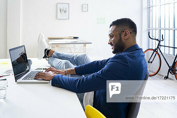 Relaxed businessman working on laptop in modern office
