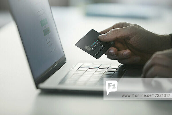 Mann  der eine Online-Zahlung per Kreditkarte auf einem Laptop vornimmt