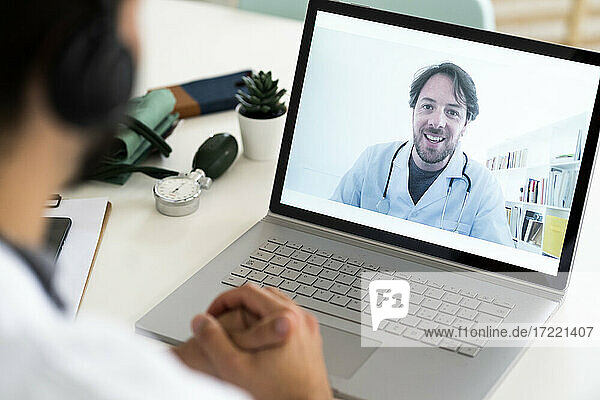 Männlicher Mitarbeiter im Gesundheitswesen bespricht sich per Videokonferenz mit einem Arzt