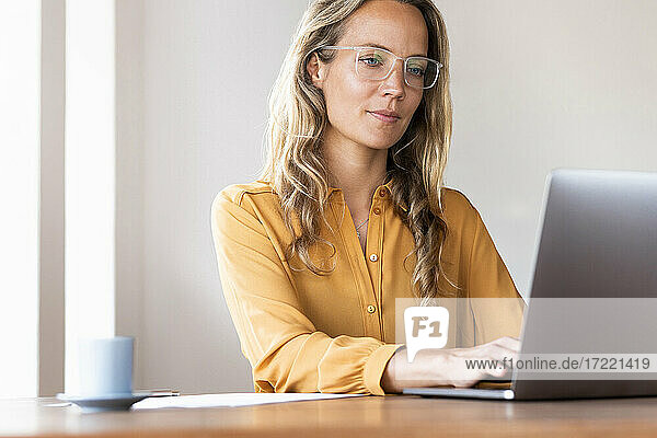 Freiberufliche Mitarbeiterin mit Laptop am Schreibtisch im Heimbüro