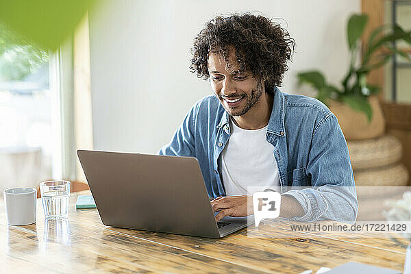 Cheerful male entrepreneur working on laptop at home