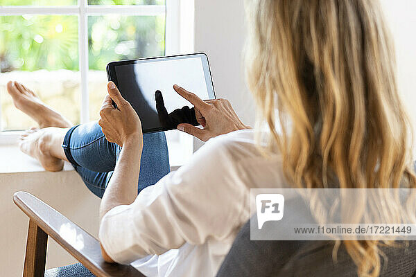 Blonde Frau benutzt digitales Tablet zu Hause