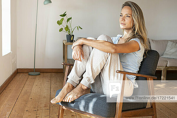 Beautiful woman contemplating while sitting on armchair at home