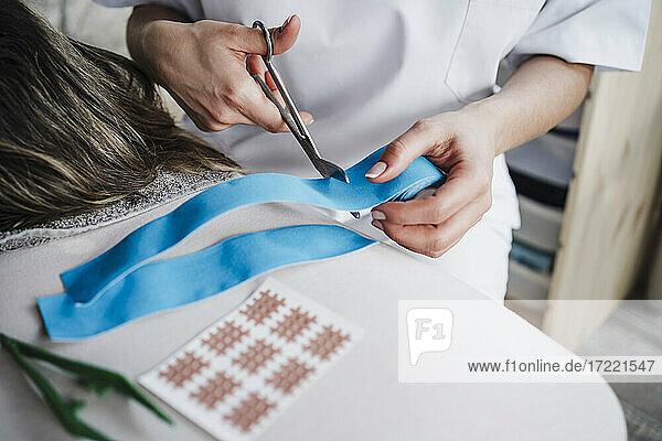Female physiotherapist cutting elastic therapeutic tape