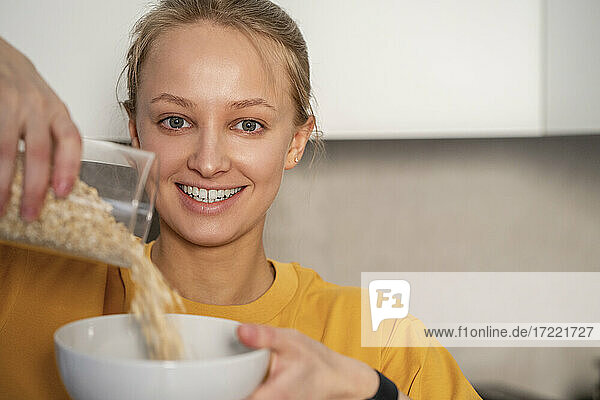 Young woman pouring food in bowl at home