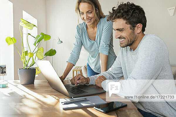 Cheerful couple working on laptop at home office
