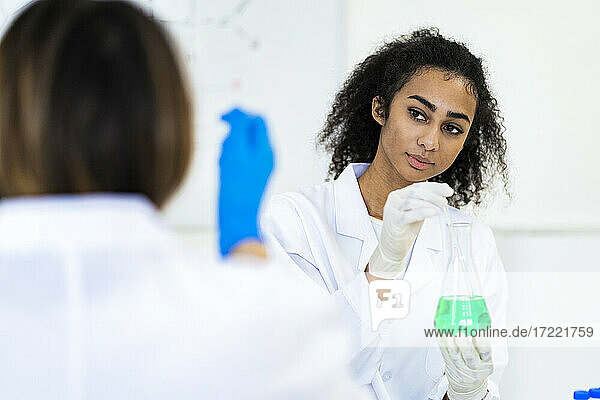 Female researcher looking at coworker while working in laboratory