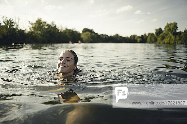 Young woman swimming in lake in summer  smiling