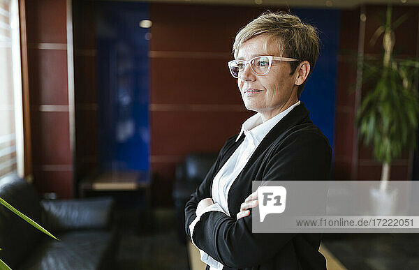 Thoughtful businesswoman looking away while standing in lobby at hotel