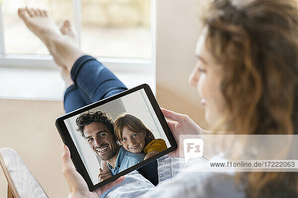 Frau führt ein Videogespräch über ein digitales Tablet  während sie zu Hause sitzt
