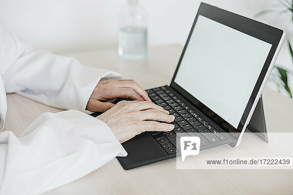 Weibliche medizinische Fachkraft  die ein digitales Tablet am Schreibtisch in einer medizinischen Klinik benutzt