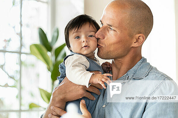 Father holding and kissing his cute baby at home