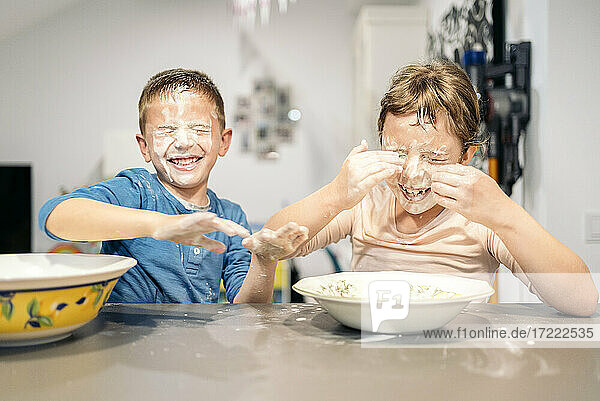 Glückliche Geschwister  die zu Hause mit Mehl und Wasser spielen
