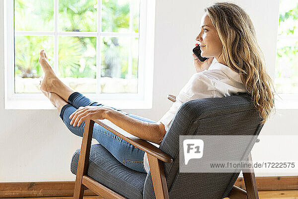 Smiling woman talking on mobile phone at home