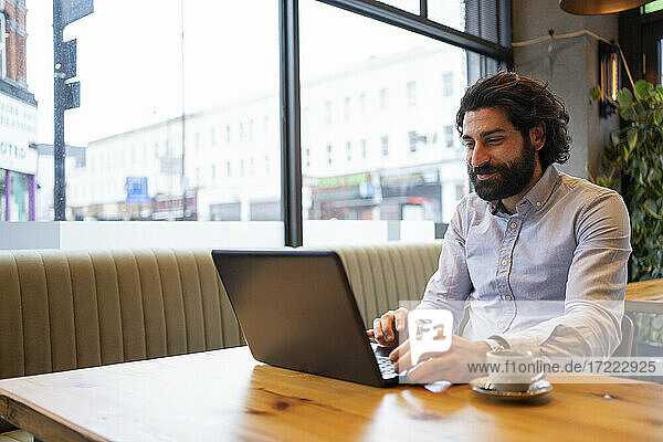 Gut aussehender Geschäftsmann  der einen Laptop benutzt  während er am Schreibtisch im Büro sitzt