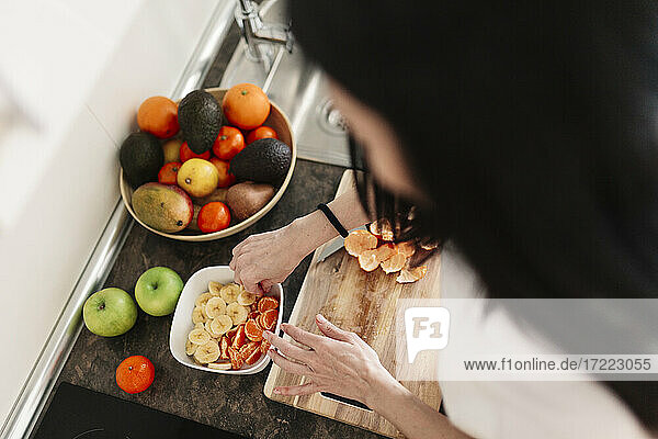 Frau bereitet Schüssel mit Früchten auf der Küchentheke zu Hause vor