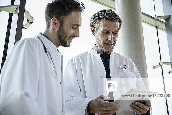 Männliche Mediziner diskutieren über ein digitales Tablet im Krankenhaus
