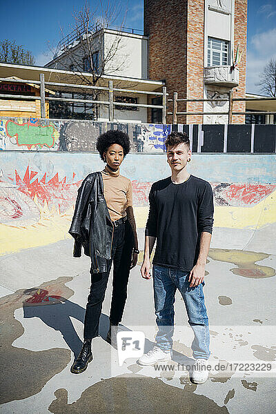 Young couple standing at skateboard park during sunny day
