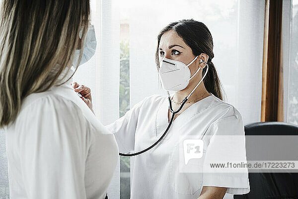Ärztin mit Gesichtsschutzmaske bei der Untersuchung eines Patienten in einer Klinik