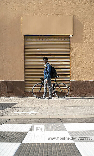 Mann mit Fahrrad an einer Mauer stehend an einem sonnigen Tag