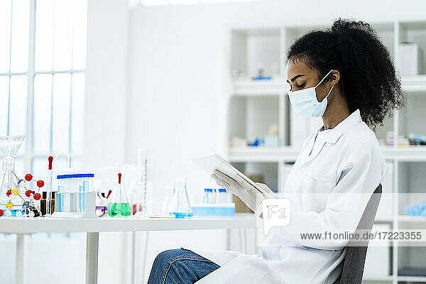 Eine Forscherin arbeitet an einem digitalen Tablet  während sie auf einem Stuhl im Labor sitzt