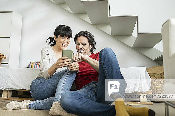 Couple discussing over smart phone while sitting at home