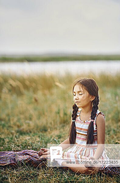 Cute girl meditating on grass