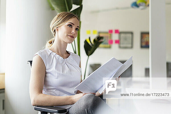 Geschäftsfrau träumt  während sie ein Dokument im Büro hält
